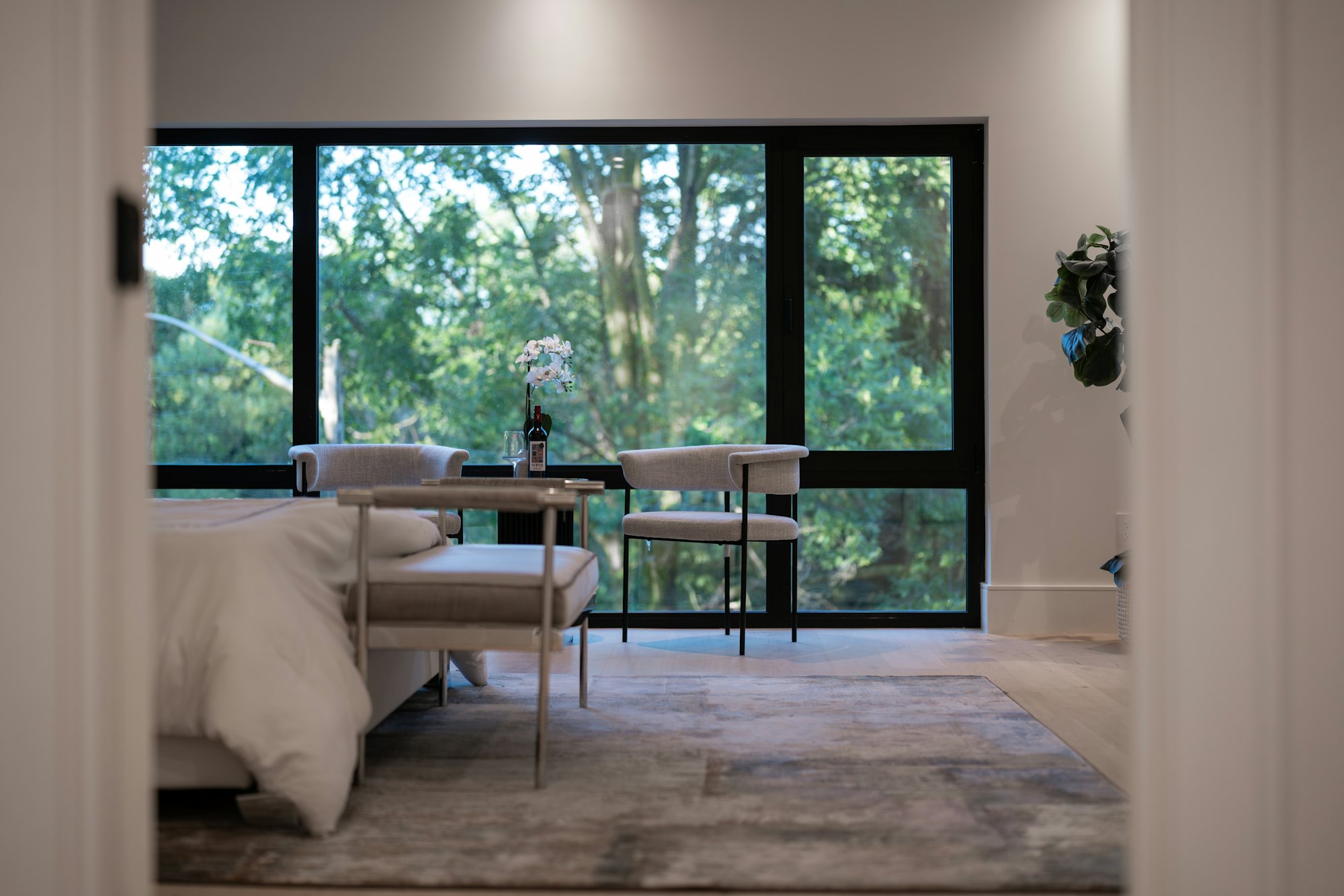 A quiet bedroom at Villa Arbolada with full-height glazing onto the canopy