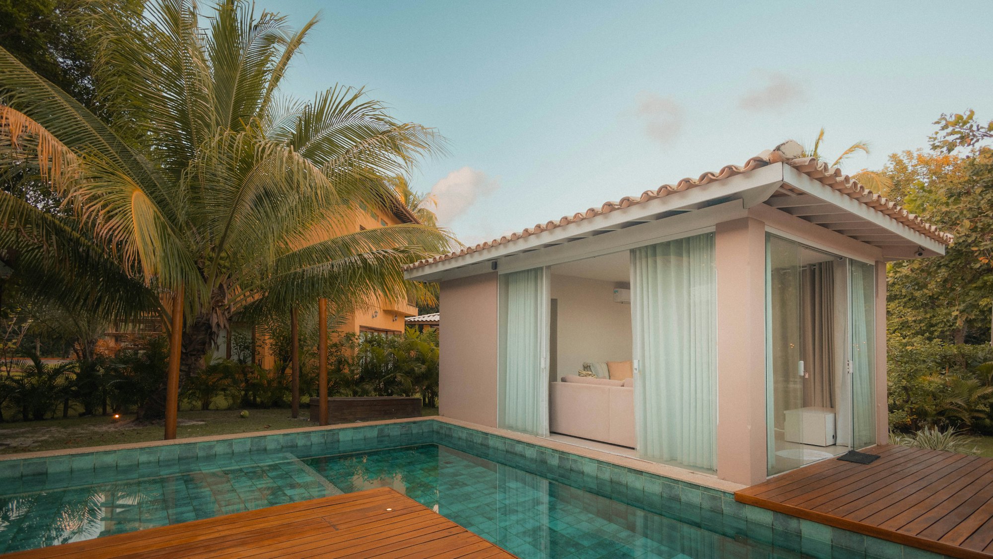White villa with a long pool and palms, a short walk from the sand