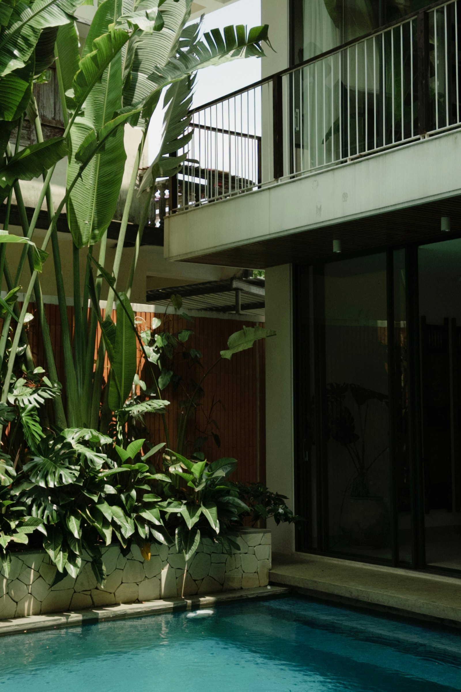 A planted courtyard beside a lit pool, enclosed by full-height glazing