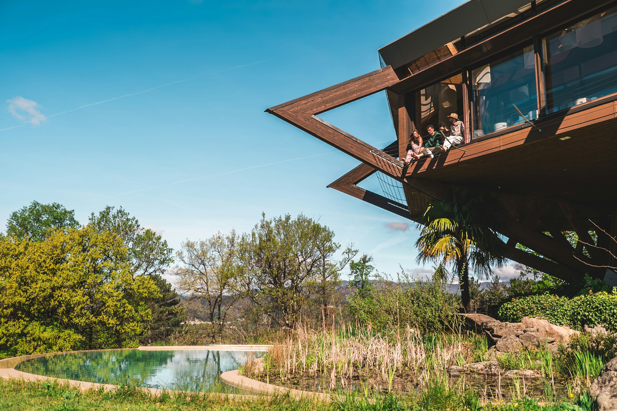 A timber-framed house cantilevered over a tropical slope