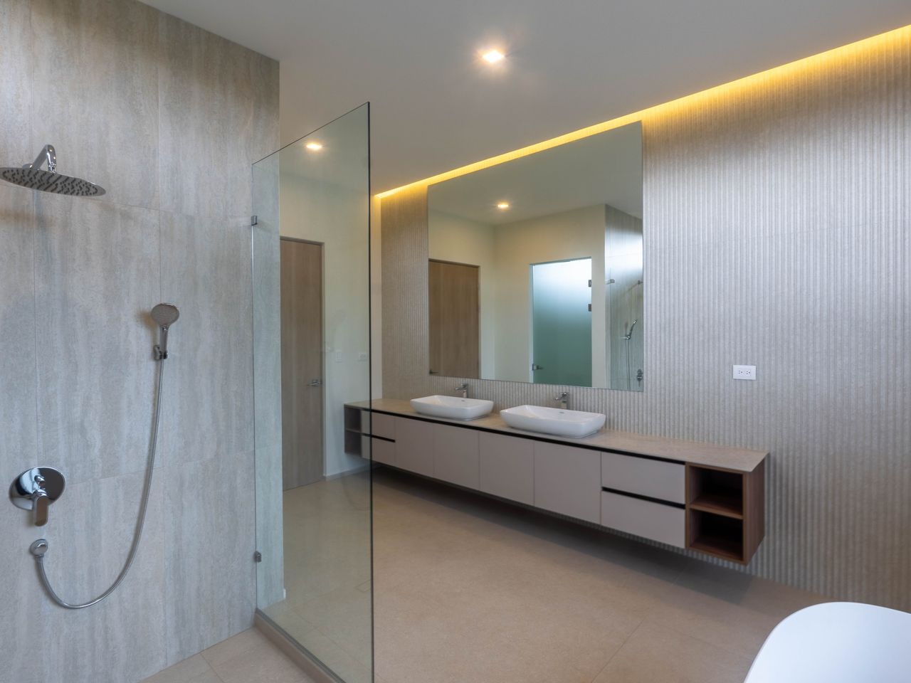 A second bathroom in pale stone with a double vanity and backlit mirror